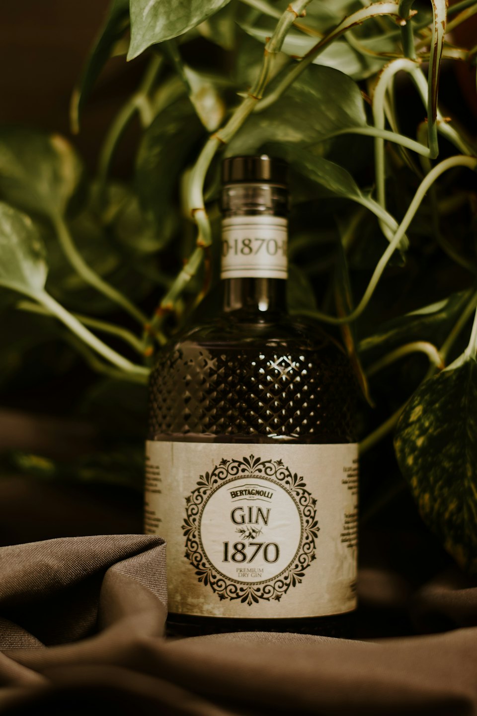 Una bottiglia di gin in vetro con motivo a rombi poggia su un tessuto.